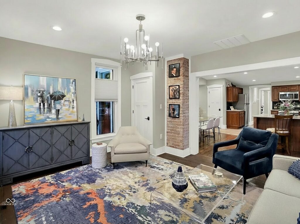 Family room with cream and navy seating, an exposed brick column, and a wide opening to the kitchen.
