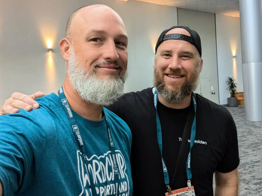 Dave Martin and Hans Skillrud smiling and posing together at WordCamp US 2024, both sporting beards and conference lanyards, reconnecting after five years.