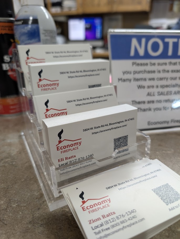 Economy Fireplace business cards with the refreshed logo and QR code in a clear acrylic holder in the showroom