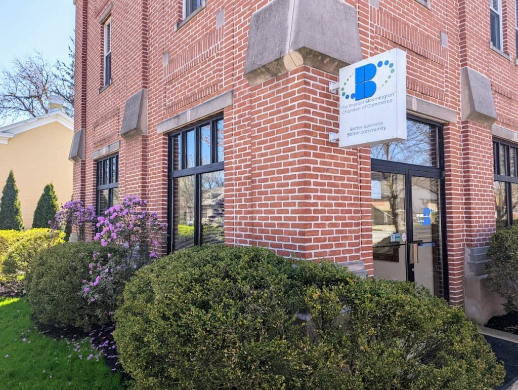 Brick exterior of the Greater Bloomington Chamber of Commerce office with its blue logo sign
