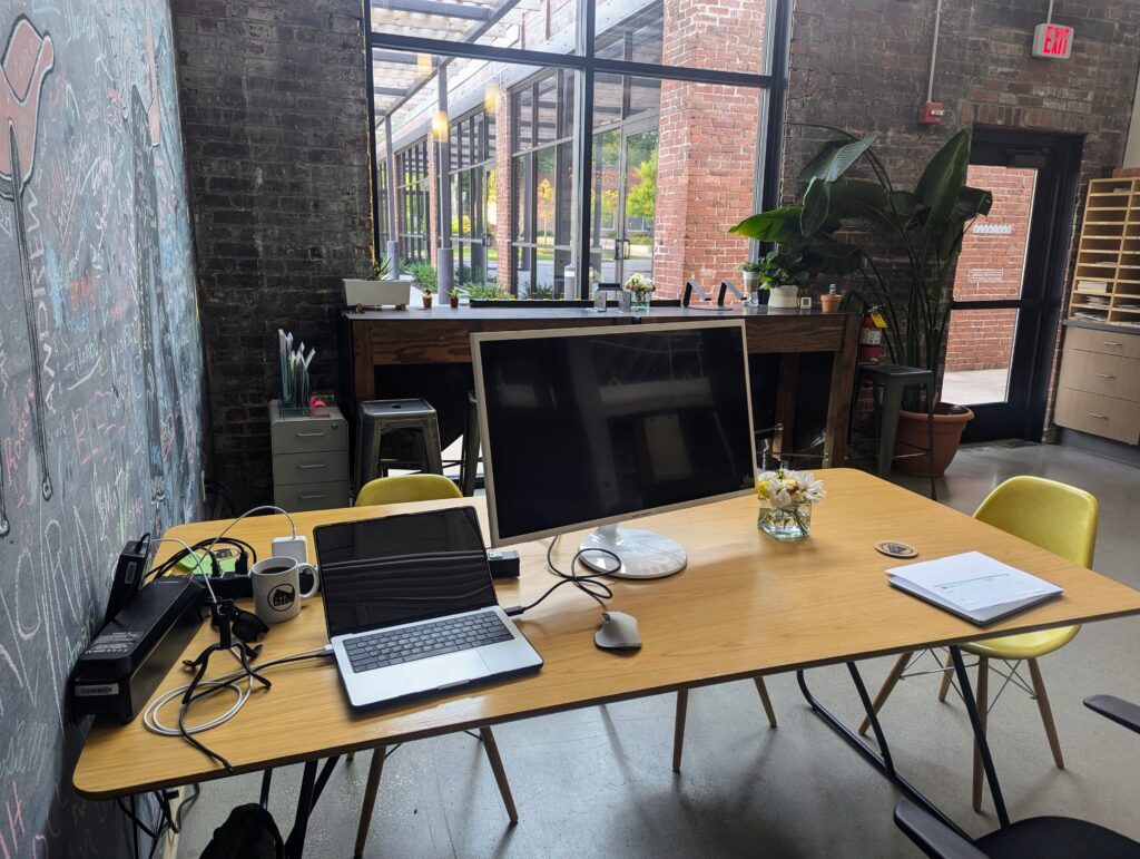 Modern workspace at The Mill, a coworking tech startup hub in Bloomington, featuring a laptop, monitor, and design tools used by David Martin Design.