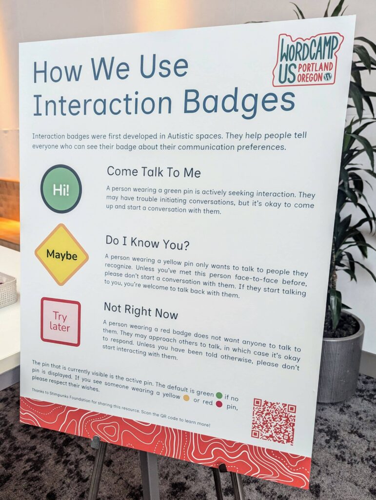 Sign at WordCamp US Portland, Oregon, explaining the use of interaction badges for communication preferences. Green "Hi!" badge indicates the person is open to conversation. Yellow "Maybe" badge indicates they only want to talk to familiar people. Red "Try later" badge indicates they do not want to engage in conversation.